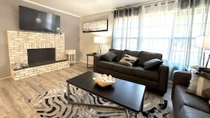 A living room with a fireplace, a sofa, a coffee table, and a zebra-patterned rug. - Beach Break House by the Surf (Daytona Beach)