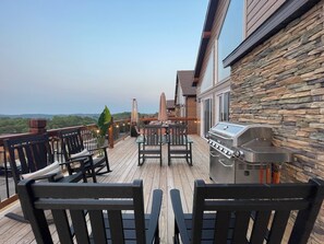 Een terras met buitenmeubilair, een barbecue en een stenen muur.