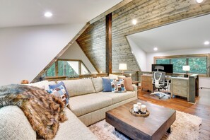 Relax in this inviting living space with a high ceiling, comfortable sofa, and large window offering a view of the outdoors.