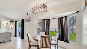 Uma sala de jantar moderna com uma mesa redonda, quatro cadeiras e um lustre.