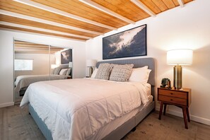 Une chambre à coucher avec un grand lit, des tables de chevet, une commode et un tableau encadré au mur.