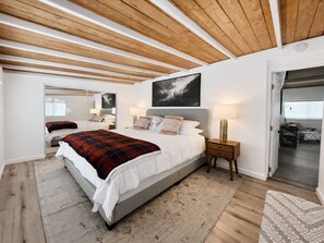 A bedroom with a bed, bedside tables, a mirror, and a painting on the wall. - Modern Crestline Cabin Near Creek & Lake Gregory (Crestline)