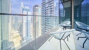 A high-rise building with a glass balcony, modern chairs, and a clear view of the cityscape.