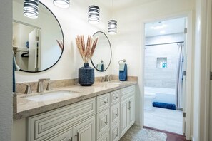 A bathroom with a double sink vanity, a large mirror, and a shower area. - Melanie's Sedona Escape (Sedona)