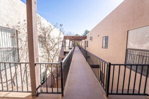 A narrow corridor with a metal railing, connecting two buildings with beige walls and windows. - Melanie's Sedona Escape (Sedona)