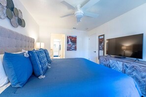 Ein Schlafzimmer mit einem großen Bett, einem Deckenventilator, einem Fernseher und einem Kabinett mit Fischgrätmuster.