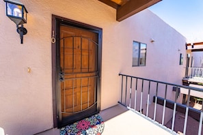 A building with a large wooden door, a small window, and a balcony with a railing.