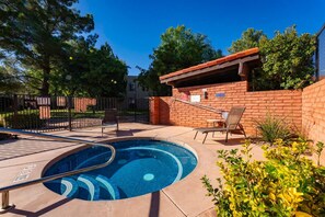 Una piscina de diseño curvo, rodeada por un muro de ladrillo y una valla de metal. Se observan sillones de descanso y una pequeña construcción de ladrillo con techo rojo.