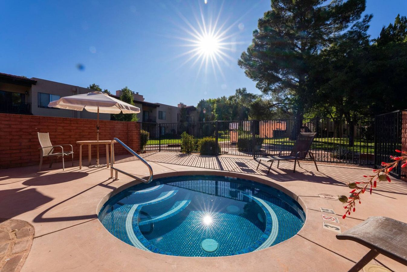 Una piscina amb una tenda de sol, una cadira i una taula.