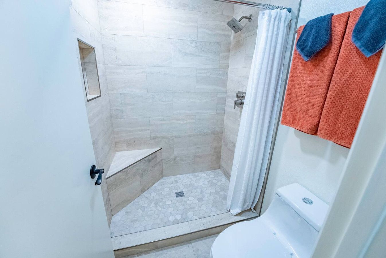 Un bagno con doccia, WC e un piccolo ripiano.