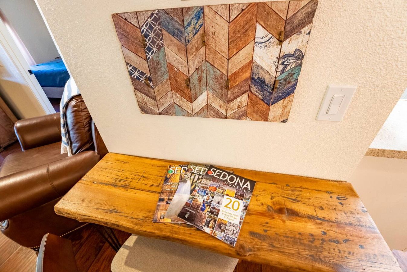 Een houten tafel met een tijdschrift met de titel 'SEDONA MONTHLY' en een kunstwerk erboven.