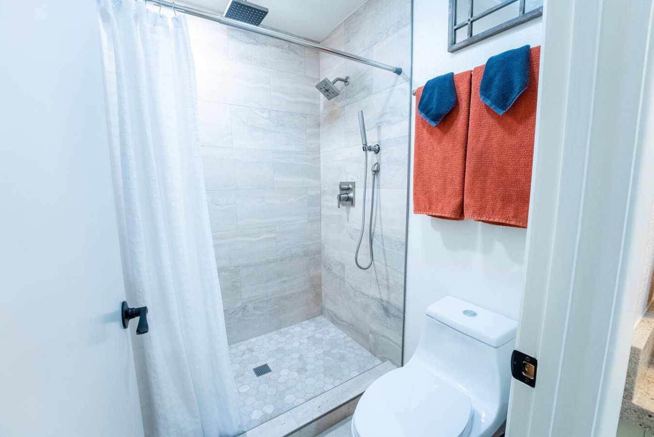 Een badkamer met een douche met glazen wand, een toilet en twee handdoeken aan de muur.