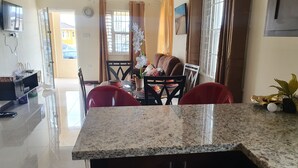 A modern kitchen with granite countertops, a dining area with a table and chairs, and a view of the outside. - Cozy retreat pool access super close to the Town. Entire home available to you! (Old Harbour)