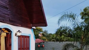 Een huis met een houten gevel, een betegeld terras en een tuin met diverse planten.