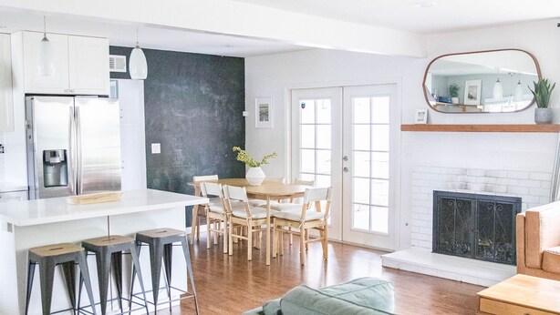 A modern kitchen with a central island, dining area with chairs, a sofa, and a fireplace. - Upscale Home w/ Private Yard (Oceanside)