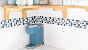 A kitchen with wooden shelves holding cups, a coffee maker, and a potted plant. - Upscale Home w/ Private Yard (Oceanside)