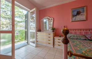 Relax in this serene bedroom with a balcony offering a view, a dresser, a mirror, and a comfortable bed.