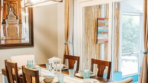 Un espace repas comprenant une table en bois, des chaises et un luminaire suspendu.
