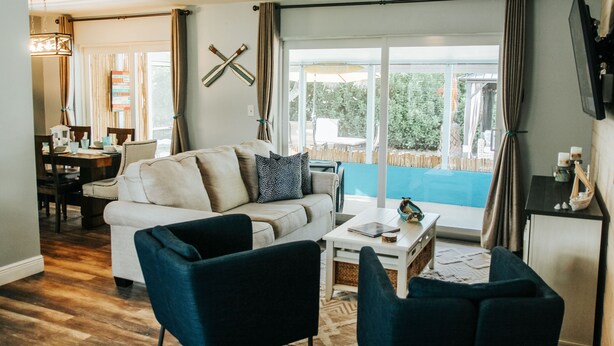 Un salon comprenant un canapé, des fauteuils, une table basse et un coin repas avec une table et des chaises.