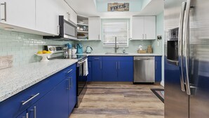 Une cuisine moderne avec des armoires bleues, des appareils en acier inoxydable et un dosseret carrelé.