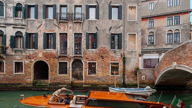 Un canal avec des bateaux, un pont et un bâtiment doté de nombreuses fenêtres et de balcons.