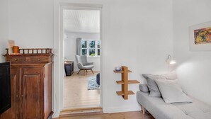 Ein Wohnzimmer mit grauem Sofa, einem Holznachttisch und einem Fernseher auf einer Holzkommode.