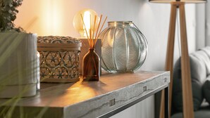 A wooden table with decorative items, a floor lamp, and a woven stool. - Sea & Sun Apartment - Pool with Sea View (Nazaré)