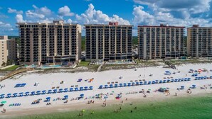 A beachfront hotel with multiple high-rise buildings, a sandy beach with umbrellas, and a clear blue sky. - January Special! - Remodeled condo on the beach super close to dining and hiking (Orange Beach)