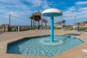 Ein Swimmingpool mit einer Wassersäule, einem hölzernen Pavillon und Blick auf den Ozean.