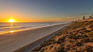 A coastal road with a beach on one side and a rocky hillside on the other. - La Costa Luxury Condo | Fully Remodeled (Carlsbad)