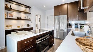 A modern kitchen with dark wooden cabinets, stainless steel appliances, and a white countertop. - La Costa Luxury Condo | Fully Remodeled (Carlsbad)