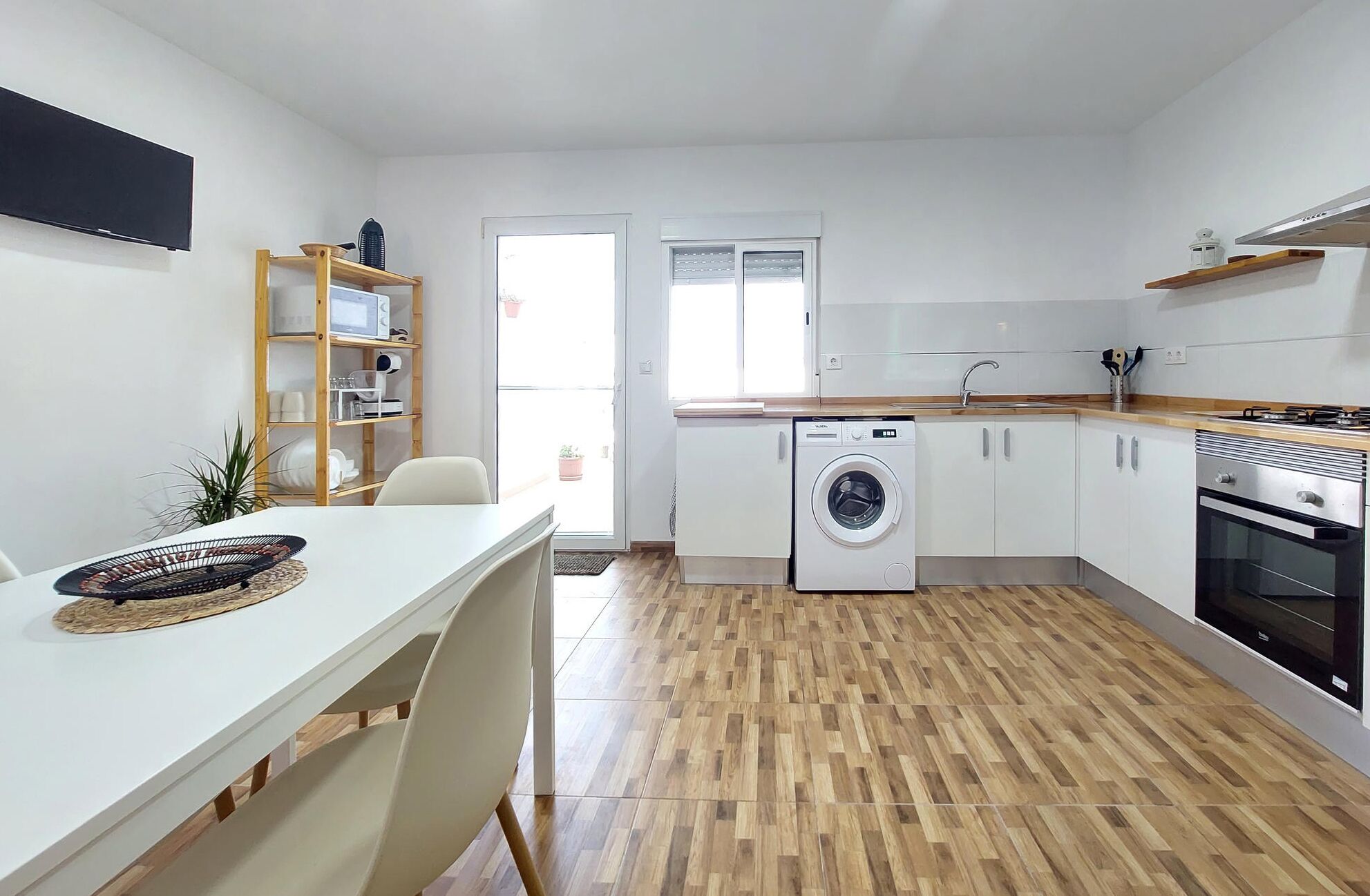 Een moderne keuken met een wasmachine, een fornuis en een eethoek met een tafel en stoelen.