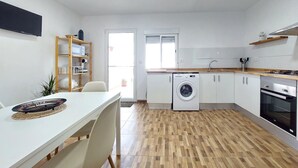 A modern kitchen with a washing machine, a stove, and a dining area with a table and chairs. - 3 bedroom stunning home in Ador (Ador)