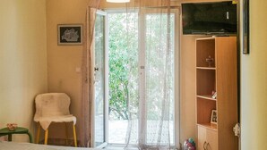 Una stanza con un letto, una sedia, un armadietto in legno e una televisione.