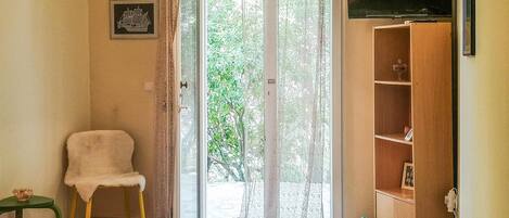 A room with a bed, a chair, a wooden cabinet, and a television.