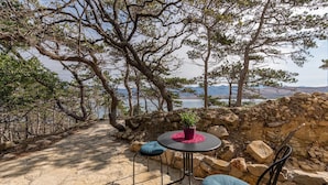A table and chairs set up on a stone patio overlooking a mountainous landscape with a view of a lake. - Cozy apartment in Novalja with WiFi (Novalja)