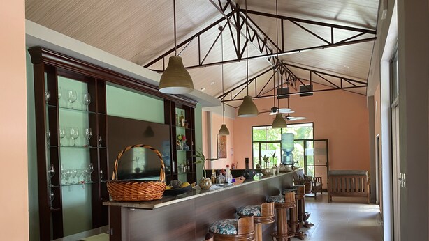 A bar area with a long counter, multiple stools, and a high ceiling with exposed beams. - Nature rich home environment, minutes away from all state parks and beach towns. (Cahuita)