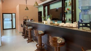 A bar area with wooden stools, a large water dispenser, and a TV mounted on the wall. - Nature rich home environment, minutes away from all state parks and beach towns. (Cahuita)