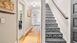 A staircase with patterned tiles, a wooden floor, and a white wall with a world map and a framed picture. - Nooga Nest - Charming 4BD, 2BA - 8 Mins From Downtown (Chattanooga)