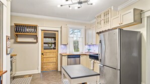 A kitchen with a stainless steel refrigerator, wooden cabinets, and a window with curtains. - Nooga Nest - Charming 4BD, 2BA - 8 Mins From Downtown (Chattanooga)