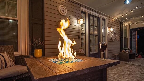 A wooden outdoor seating area with a fire feature, a glass table, and a potted plant. - Nooga Nest - Charming 4BD, 2BA - 8 Mins From Downtown (Chattanooga)
