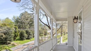 A covered porch with a metal bird feeder, white railings, and a lantern. - Farmhouse Writer's Retreat in Historic Shepherdstown (Shepherdstown)