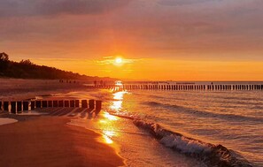 A sunset over a beach with a wooden pier extending into the water. - Nice home in Gdynia with house a panoramic view (Gdynia)