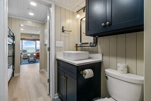 A modern bathroom with a white sink, dark cabinetry, and a visible toilet paper holder. - [Amazing gulf views, 1 BR+bunkroom, free beach chairs, walk to Pier Park] (Panama City Beach)