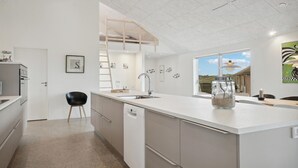 Una cocina moderna con una isla central, lavavajillas y ventana con vistas al exterior.