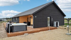 Una cabaña moderna con jacuzzi, terraza de madera y un letrero con el número 29.