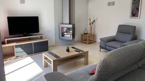En moderne stue med et fladskærms-tv, en pejs, en grå sofa og et sofabord.