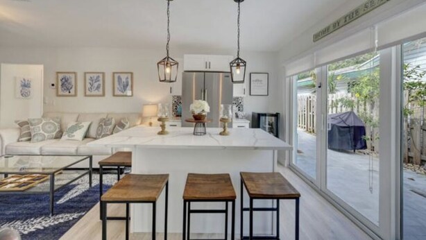 Una cocina moderna con una isla central, iluminación colgante y vistas al exterior.