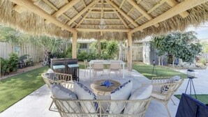 Un patio techado con mobiliario de mimbre y techo de paja.