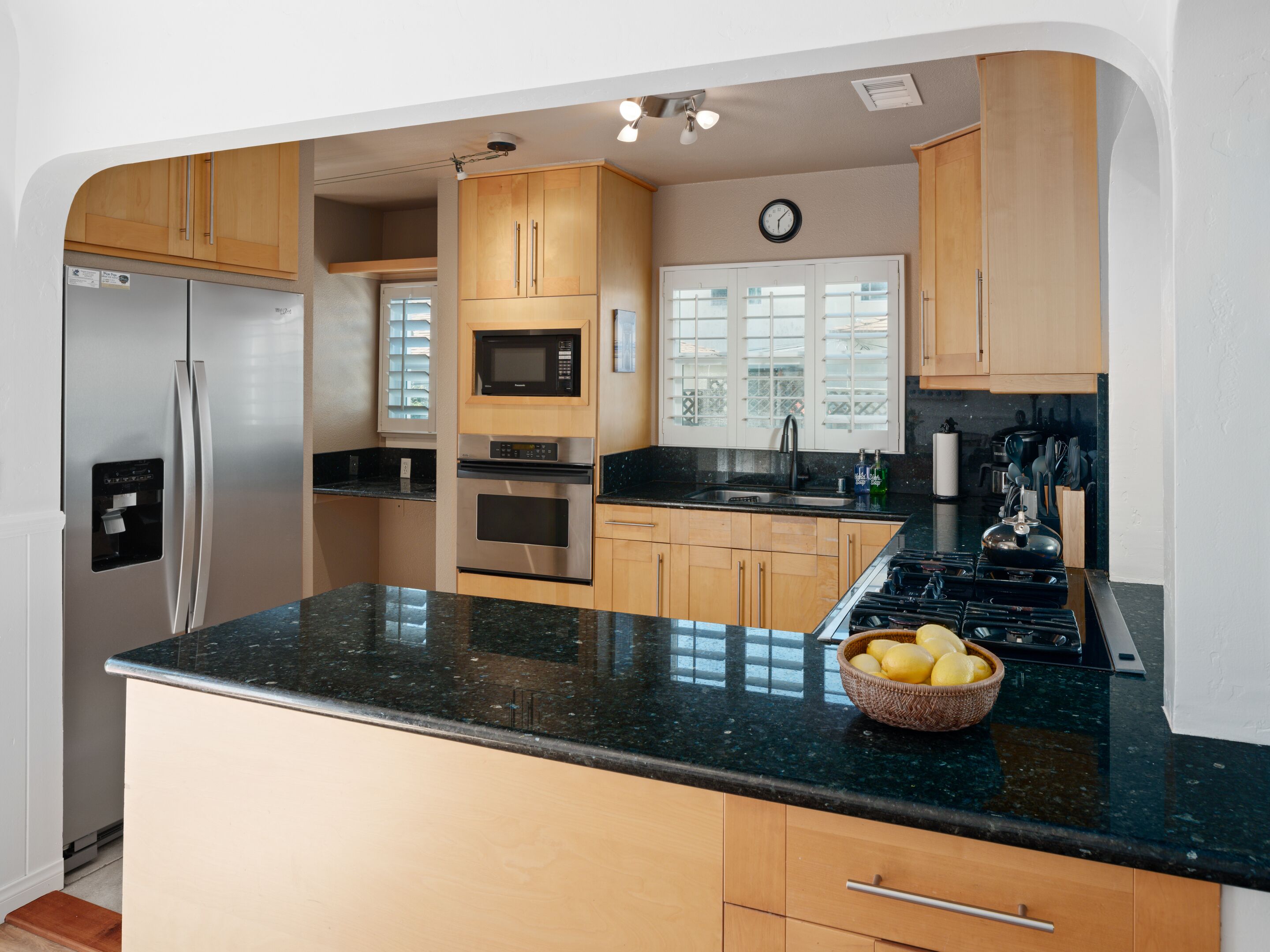 Una cocina moderna con electrodomésticos de acero inoxidable, armarios de madera y encimera de granito.